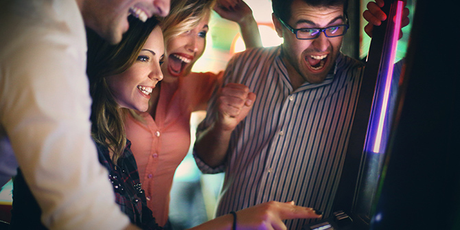 Group of four happy people at a slot machine